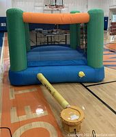 Front view of assembled inflatable bounce house on gym floor with attached blower and safety mesh netting