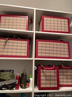 Two large plaid bins on top white shelf