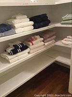 Shelf with 5 coordinating towel sets folded, showing various colors including white, navy, beige, pink, and light blue.