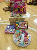 Overview of all items in lot including two boxed Shopkins playsets, Littlest Pet Shop board game, assorted figures on tray and bags