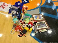 Group photo showing all items including Ariel sculpture, plush toys, framed prints, Nemo play phone, umbrella, and more on gym floor.