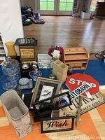 General lot overview showing glass bowls, jars, vase, desk organizer, floral arrangement, framed signs, spice box, and waste bin