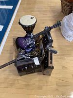 Overall lot view showing two WowWee NXT guitars with patterned bodies, Toca Percussion djembe, black and silver cables, and equipment cases