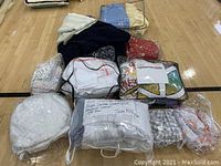 Multipack of folded throw blankets and comforters in plastic bags on gym floor, mixed colors and patterns