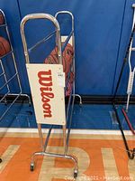 Front view of Wilson metal basketball ball rack with Wilson logo and basketballs inside.