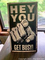 Front view of the vintage tin sign showing raised pointed hand and text HEY YOU GET BUSY!