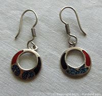 Front view showing both circular open silver rings with colored inlays on white fabric background.