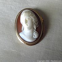 Front view of oval cameo showing white relief bust and gold frame