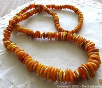 Full view of honey amber nugget necklace laid on fabric, showing color and texture of beads.