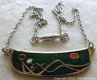 Front view of the vintage 1960s enamel pendant necklace showing colorful abstract seaside couple design on a silver tone base with chain and clasp.