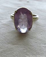 Front view of oval faceted light amethyst set in sterling silver band with hand prong and filigree work.