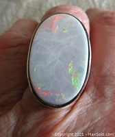 Top view of bezel-set oval white opal showing green and orange play-of-color