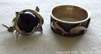 Ring and pendant displayed together on light fabric background showing silver band and black onyx pendant
