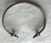 Top view of a twisted sterling silver cable bracelet with malachite capped ends, displaying its open-ended design.