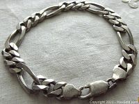 Full view of the vintage sterling silver Figaro link bracelet on a light fabric background, showing the link design and clasp.