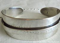 Close-up photo showing the top and side profile of the silver modernist bangle bracelet with the open cuff and raised central ridge design.
