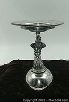 Front view of entire silver plate tray and figural stand showing height and reflective surfaces.