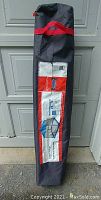 Screen house in its black storage bag with red trim and label showing the product name and dimensions.