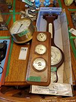 Photo shows wooden plaque with clock, barometer, and hygrometer dials alongside round brass pressure gauge and banjo-style barometer