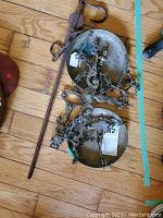 Antique brass balance scales laid down, showing ornate scroll and floral pattern work on the frame and arms, with two matching brass pans attached by chains.