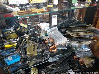 Wide view of glass cabinet shelf with numerous HO scale model train tracks, controllers, and accessories including yellow Tyco controller and blue Life-Like controller.