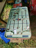 Full top view of vintage metal tabletop hockey game with player rods and puck on playing surface.