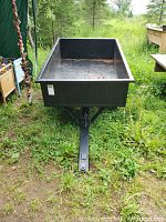 Front view of black metal utility trailer showing rectangular bed and hitch arm