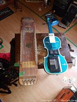 Full view of the wooden Ukelin lap harp and the blue violin-shaped Panasonic radio cassette player side by side on a wooden table.