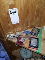 Eight vintage lighters arranged on a wooden surface, some in cases or boxes, varying styles and materials.