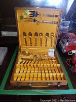 Full view of open wooden case showing entire bronze cutlery set inside velvet lining.