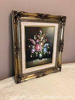 Framed floral artwork with detailed ornate gold frame showing front and side angle