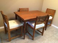 Full view of teak table and four wicker cane back chairs from angle