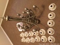 Full view of chandelier with arms and detached cream translucent glass bulb shades laid out on carpeted floor, showing color, shape, and finish of metal frame.