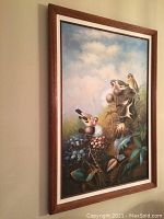 Angled view of full framed oil painting showing three birds perched on thistle plants against cloudy sky