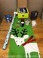 Photo of entire lot showing green Rudolph table runner, candles, box of ornaments, snow globe, rolls of wrapping paper, and packaging for lights.