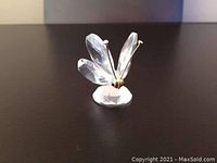 Clear crystal butterfly figurine with gold-toned antennae shown on dark surface