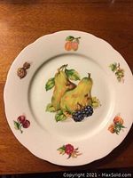 Individual plate with pears, grapes, and mixed fruit patterns detailed in color with gold rim on white fine bone china, scalloped edge.