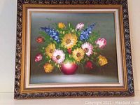 Front view of the oil painting showing the bouquet of colorful flowers in a red vase within an ornate frame.