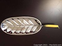 Stainless steel leaf-shaped serving tray with yellow handle, photo from the top showing entire item.