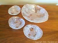Close-up photo of the glass serving set with platter and bowls arranged on the wooden surface.