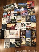 Collection of hardcover and softcover books spanning various genres such as fiction, nonfiction, economics, LSAT test prep, and self-help, arranged on wood floor.