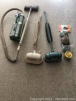 Full lot showing Electrolux vacuum with hose, Regina and GE floor polishers, polish wax, buffer pads, steel wool pads, and extra vacuum bags.