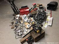 Overall view of lot including toolboxes, assorted power and hand tools, chainsaws, and accessories arranged on concrete floor.