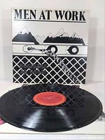 Front view of the Men At Work "Business As Usual" vinyl record album cover and vinyl record showing CBS red label