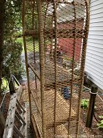 Side view of rattan shelving unit showing five woven shelves and lattice side panels on outdoor deck