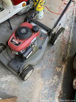 Side view of the Black Max self-propelled lawn mower showing red Honda GCV engine, wheels, and grass catcher.