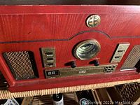 Front view of vintage stereo system showing center analog tuner dial, control buttons, and side speaker grills