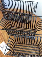 Three black metal holdall baskets in small, medium, and large sizes nested inside each other on a wooden surface.