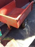 Photo showing the red garden wagon from a side angle, highlighting the bed and hitch connection.