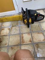 Full side view of black and yellow McCulloch chainsaw with yellow protective chain cover on tiled floor.
